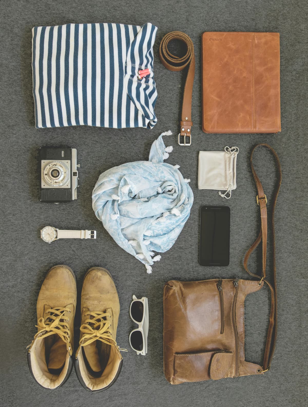Shoe, glass, bag, belt and cloth on a gray rug